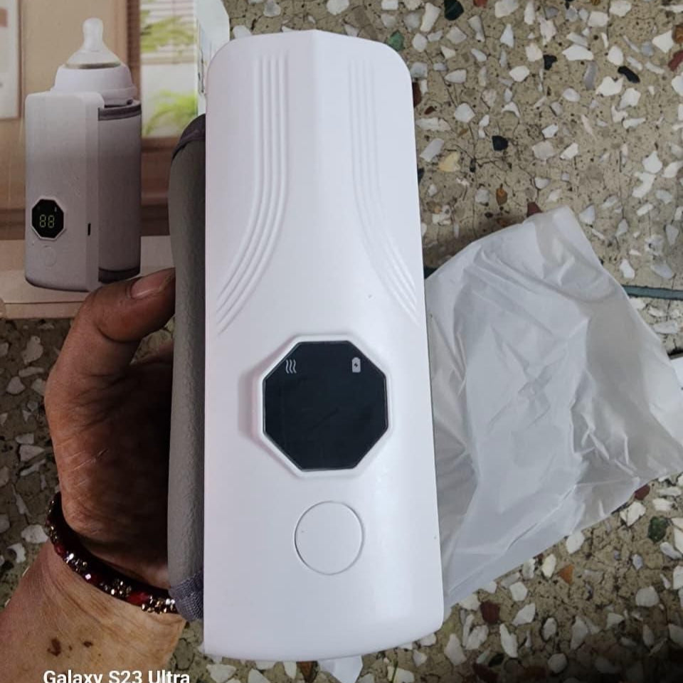 White electronic device held by a hand on a textured surface