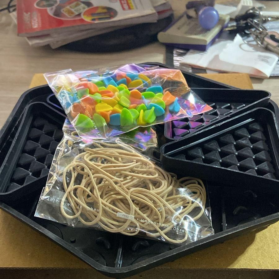 Packaged rubber bands and colorful plastic items on a black tray with a computer keyboard in the foreground.