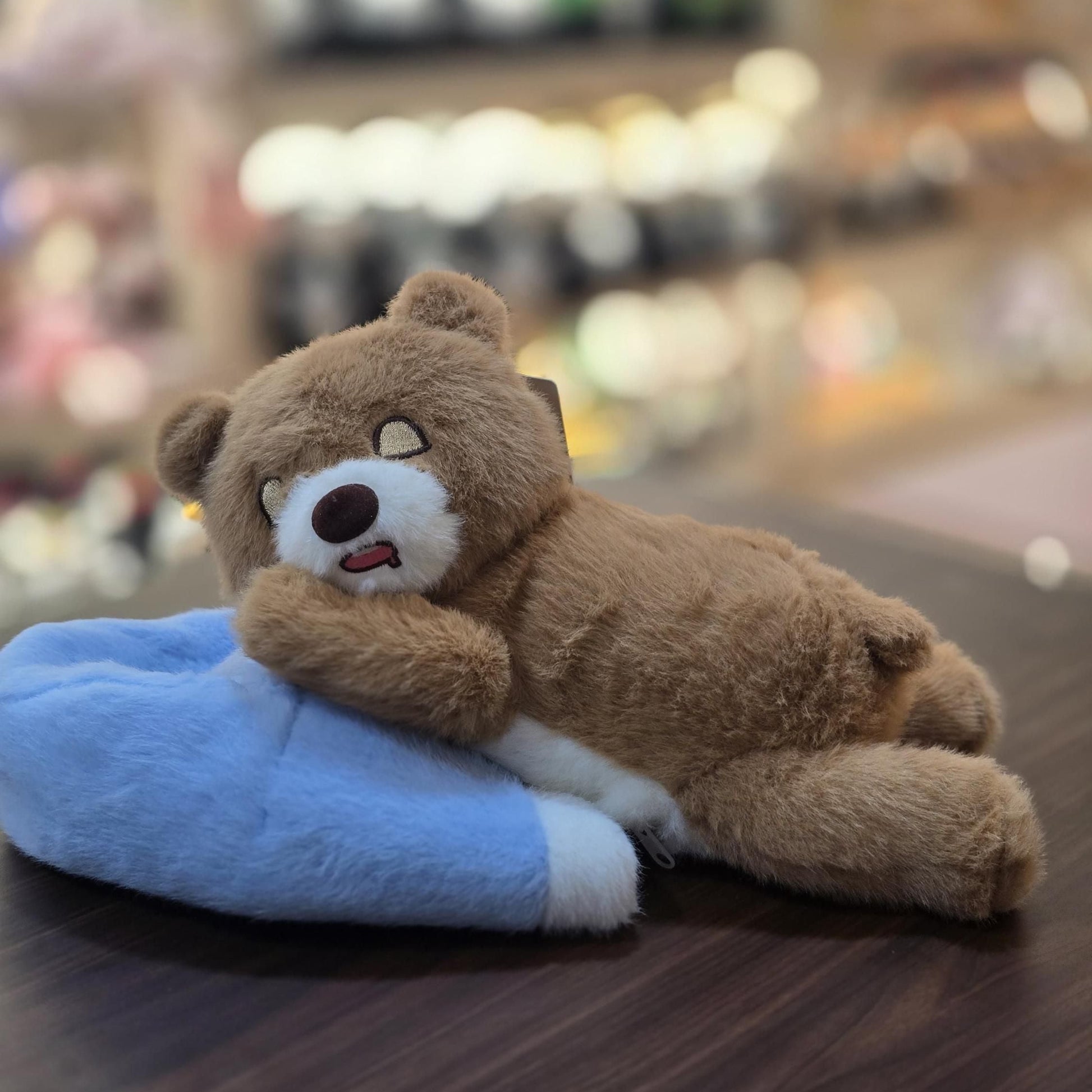 Plush teddy bear lying on a blue pillow with a blurred background